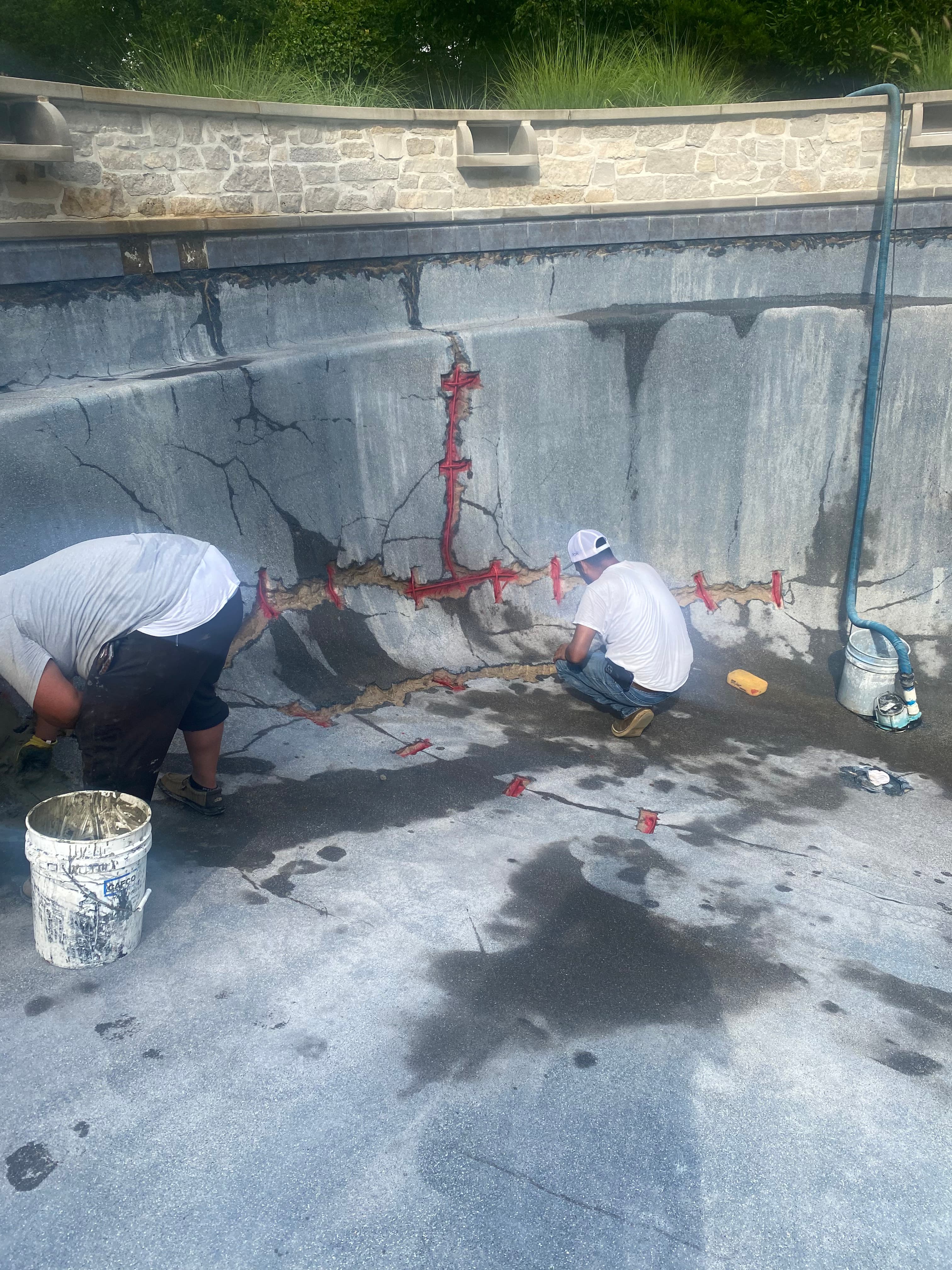 Workers repairing structural cracks in a commercial pool shell.
