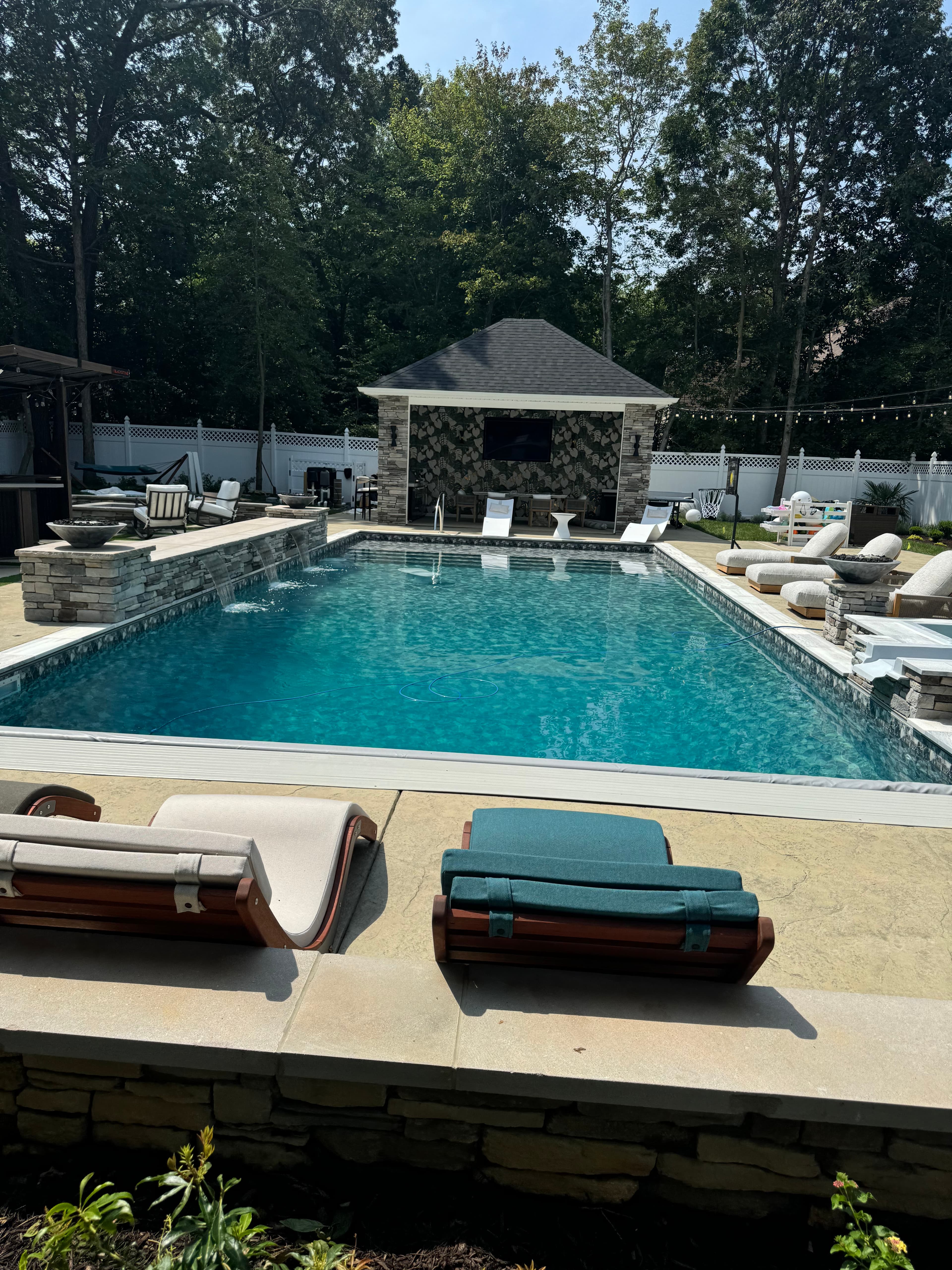 Finished custom pool with tanning ledge, stone accents, and pool house.