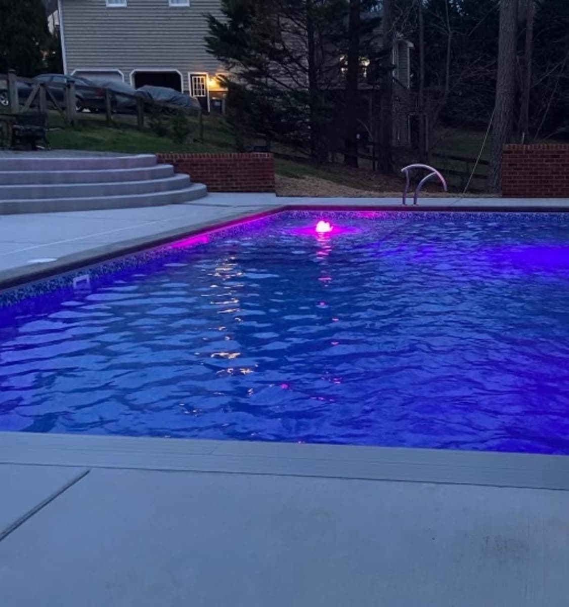 Completed pool with blue LED lighting and stone deck.