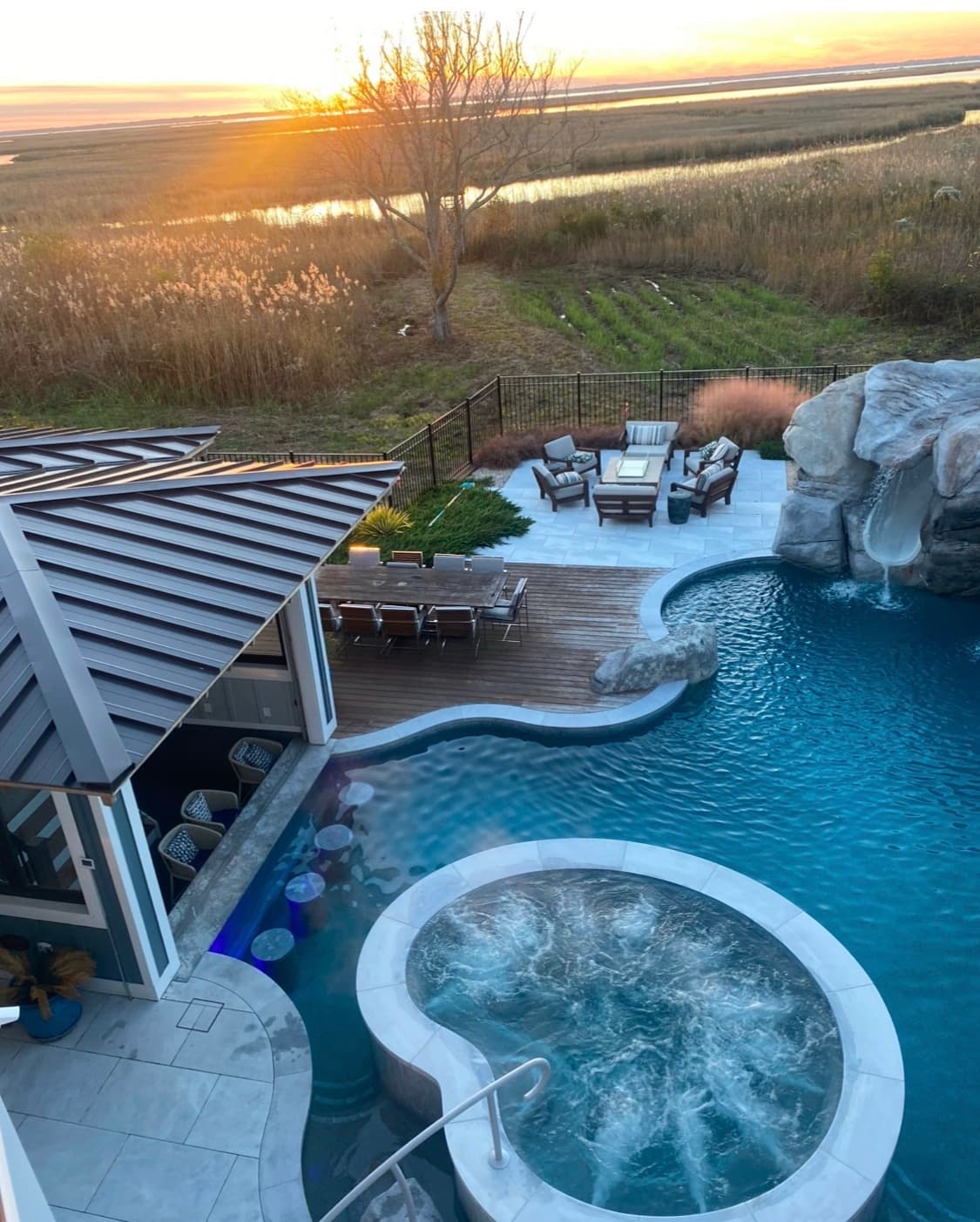 Spillover spa integrated into a custom pool with grotto and outdoor living at sunset.
