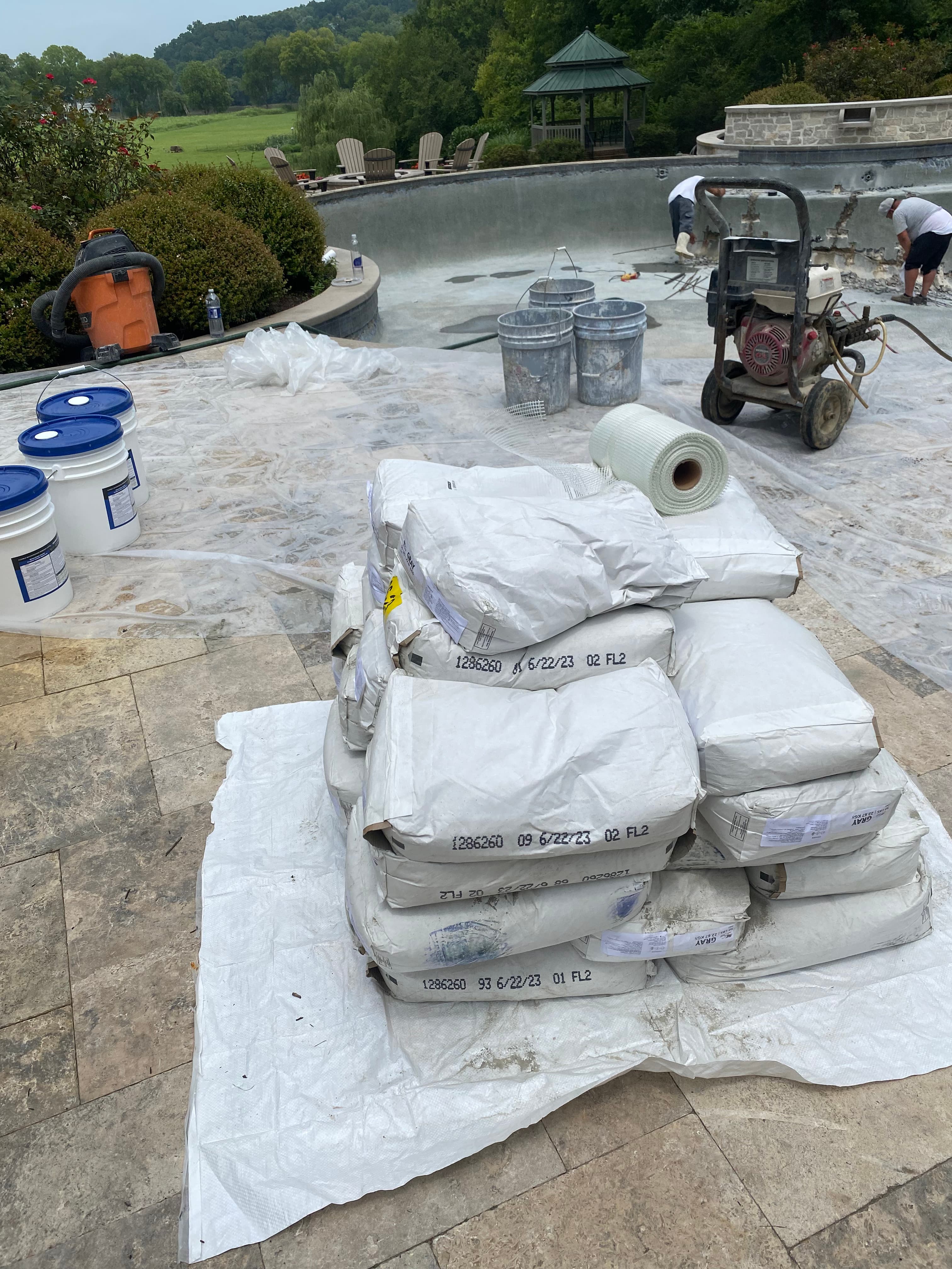Large commercial pool with stone deck and gazebo during replastering.