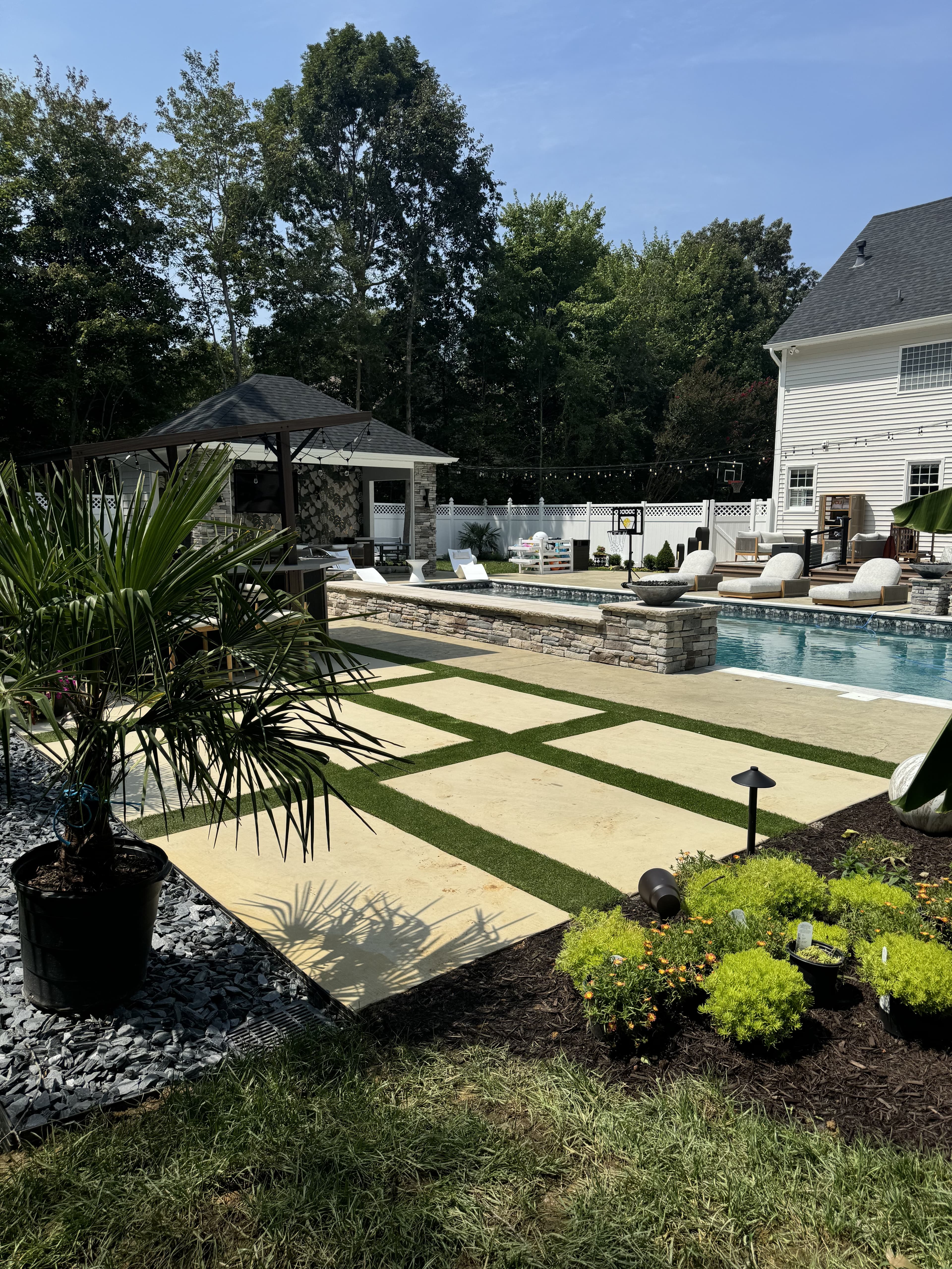 Finished pool with premium stone decking, landscaping, and pool house.